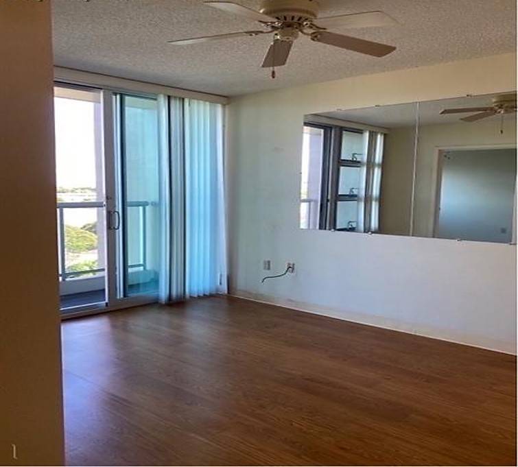 A room with a ceiling fan and sliding glass doors.